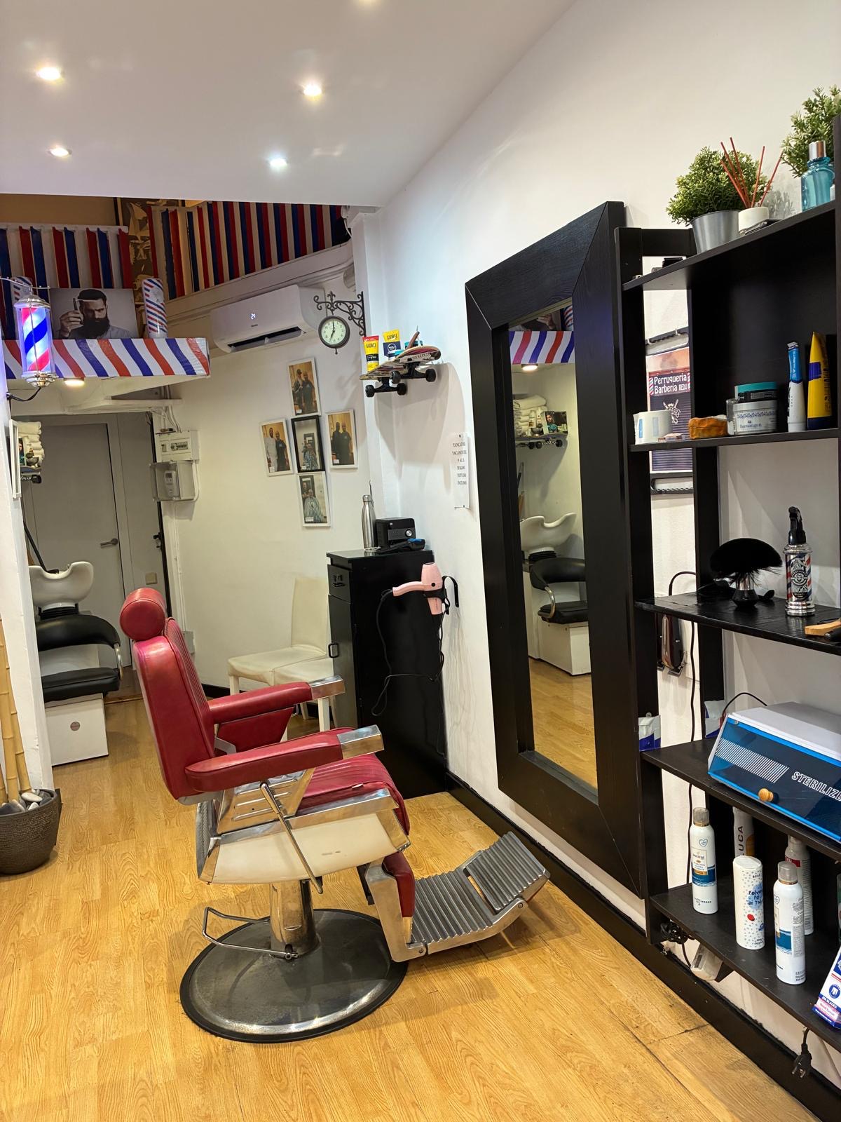 Interior de la barbería con espejo grande y muebles negros